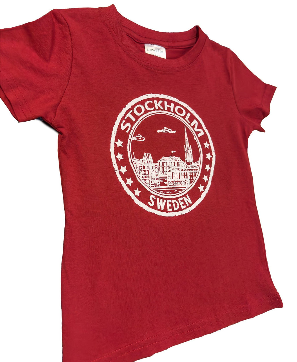 Side View of  Seal of Stockholm Children’s T-Shirt In Red Cotton featuring iconic Stockholm skyline and “Stockholm, Sweden” badge design. Sweden souvenir - Style Council 