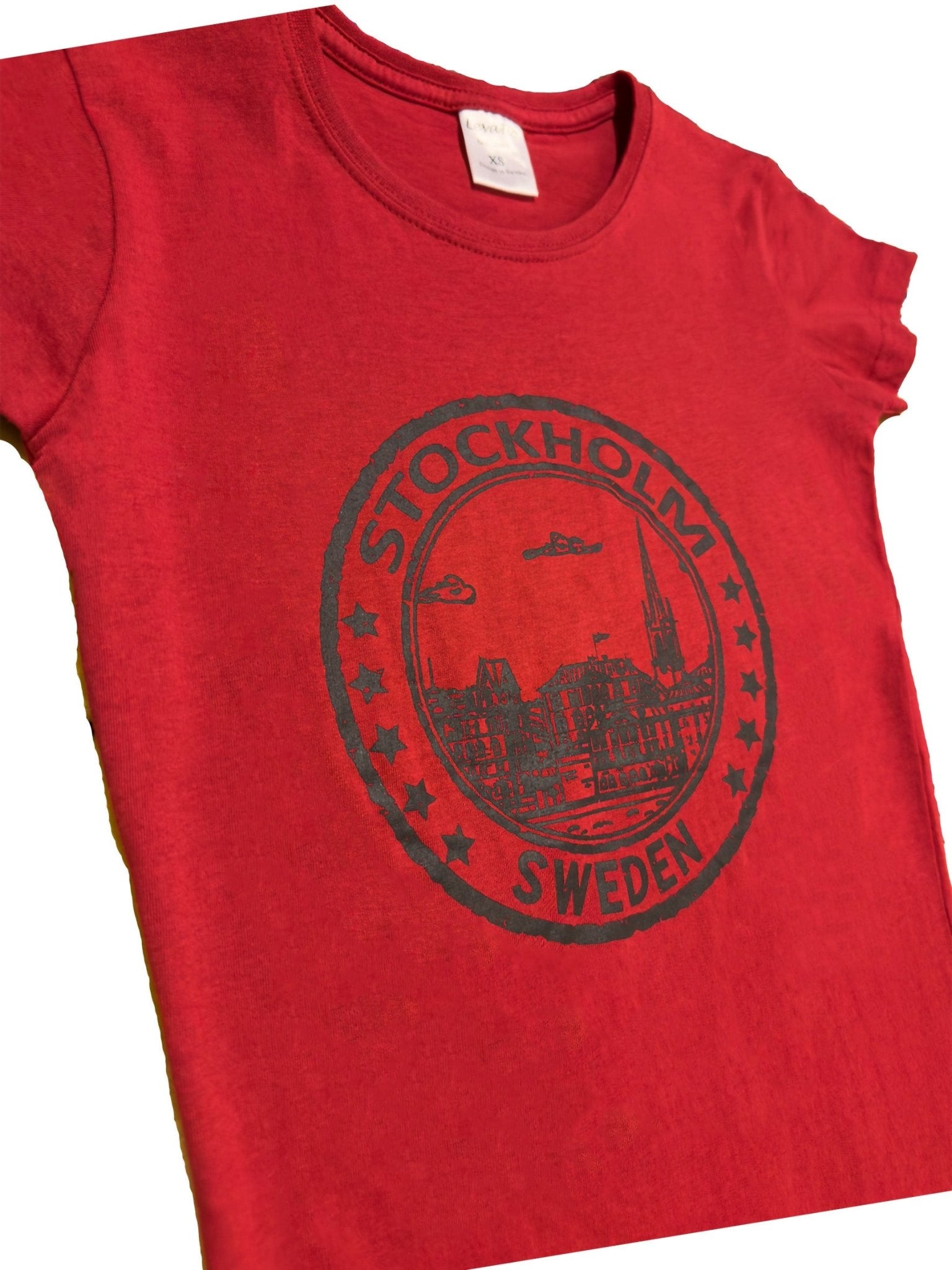Side View of Women’s t-shirt in red with Stockholm cityscape seal and “Stockholm Sweden” text. Soft cotton - Style Council
